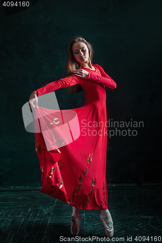 Image of Ballerina posing in pointe shoes at black wooden pavilion