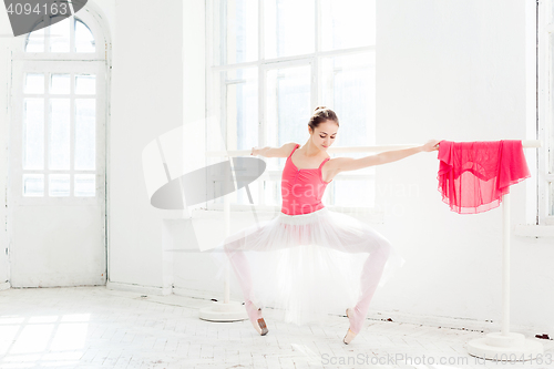 Image of Ballerina posing in pointe shoes at white wooden pavilion