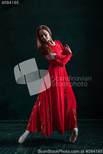 Image of Ballerina posing in pointe shoes at black wooden pavilion