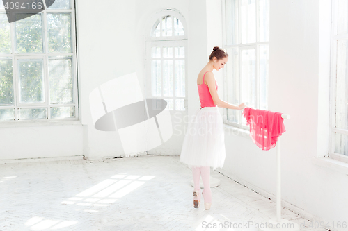 Image of Ballerina posing in pointe shoes at white wooden pavilion