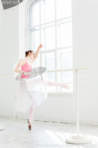 Image of Ballerina posing in pointe shoes at white wooden pavilion