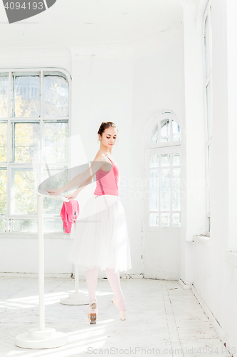 Image of Ballerina posing in pointe shoes at white wooden pavilion