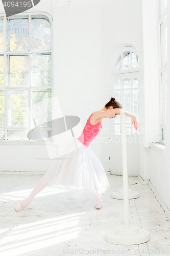 Image of Ballerina posing in pointe shoes at white wooden pavilion