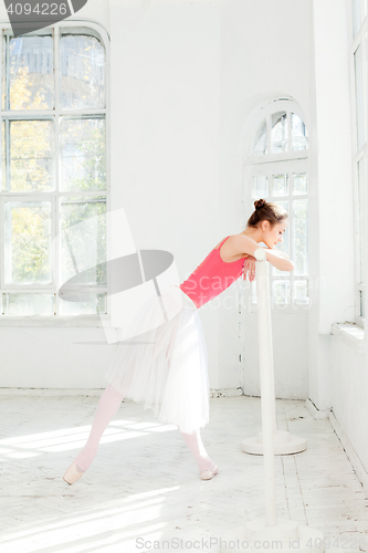 Image of Ballerina posing in pointe shoes at white wooden pavilion