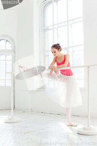 Image of Ballerina posing in pointe shoes at white wooden pavilion