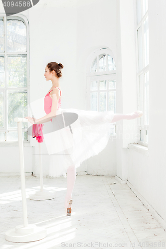 Image of Ballerina posing in pointe shoes at white wooden pavilion