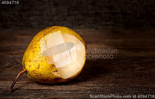 Image of One bitten pear lying on a wooden table