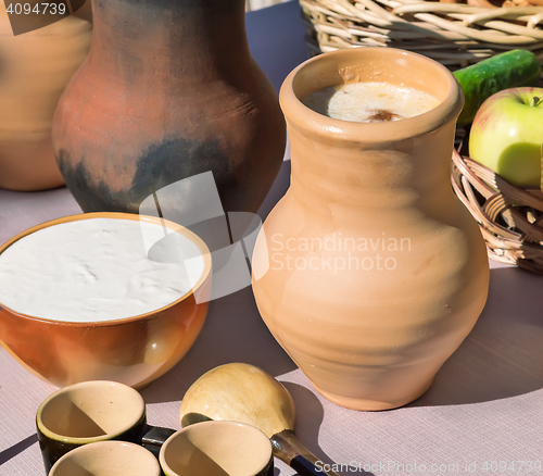 Image of A jug of warm milk and a Cup of sour cream.