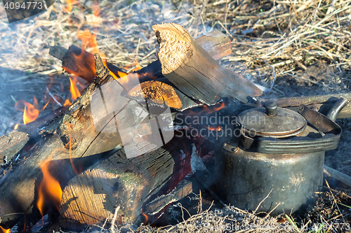 Image of Burning fire and a kettle near the fire.