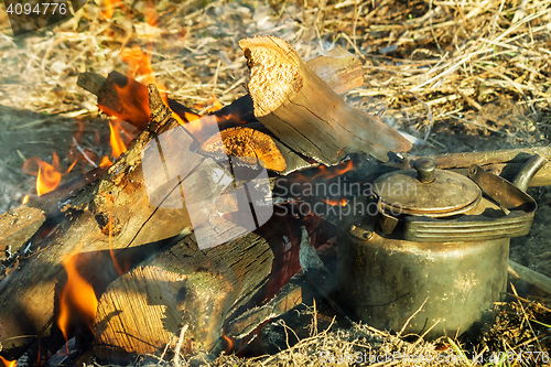 Image of Burning fire and a kettle near the fire.