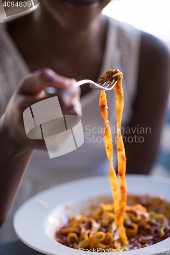 Image of a young African American woman eating pasta