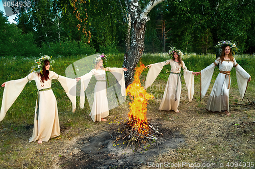 Image of Beautiful women with flower wreath near bonfire