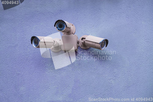 Image of Three security cameras on blue wall