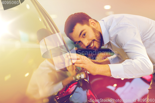 Image of happy man touching car in auto show or salon