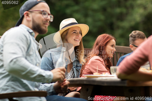 Image of happy friends having dinner at summer garden party