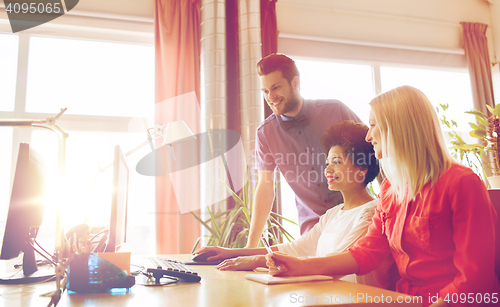 Image of happy creative team with computer in office