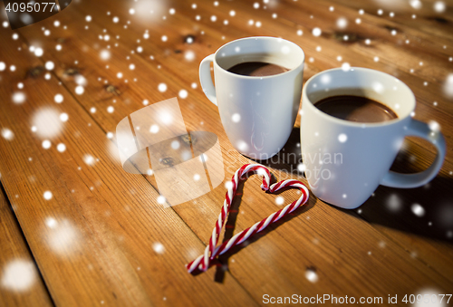 Image of christmas candy canes and cups on wooden table