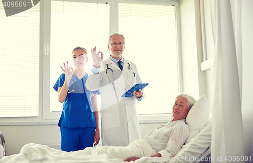 Image of doctor and nurse visiting senior woman at hospital