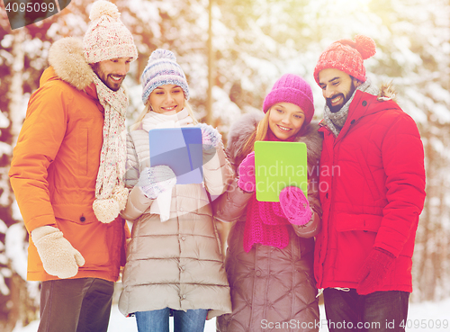 Image of smiling friends with tablet pc in winter forest