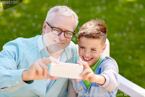 Image of old man and boy taking selfie by smartphone