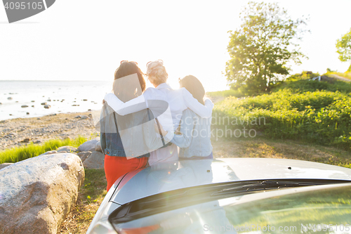 Image of happy teenage girls or women near car at seaside