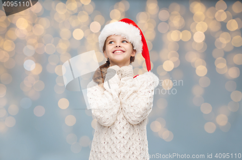 Image of girl in santa hat dreaming over christmas lights