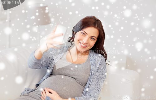 Image of pregnant woman taking smartphone selfie at home