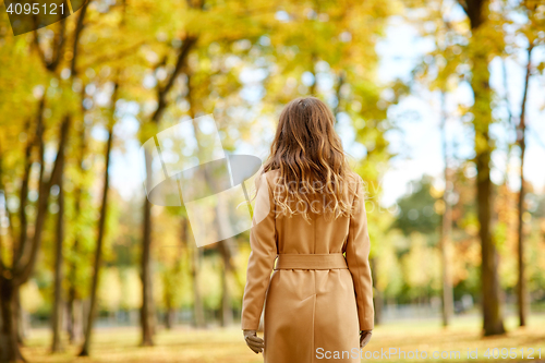Image of beautiful young woman walking in autumn park