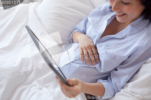 Image of close up of pregnant woman with tablet pc at home