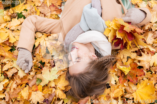 Image of beautiful happy woman lying on autumn leaves