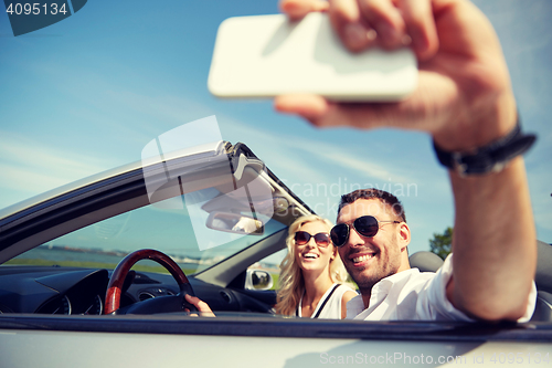 Image of happy couple in car taking selfie with smartphone