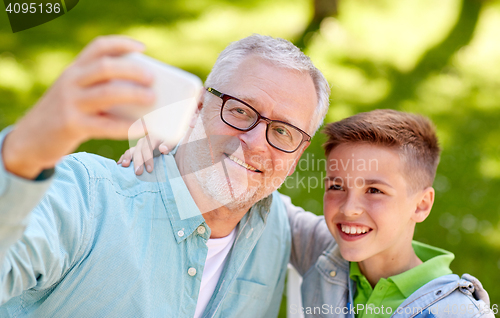 Image of old man and boy taking selfie by smartphone