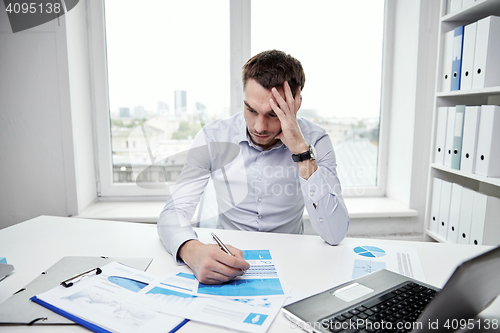 Image of stressed businessman with papers in office