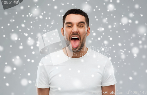 Image of man showing his tongue over snow background