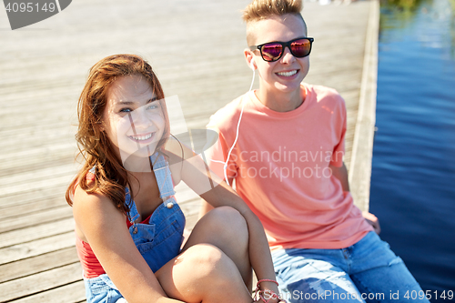 Image of happy teenage couple with earphones on river berth