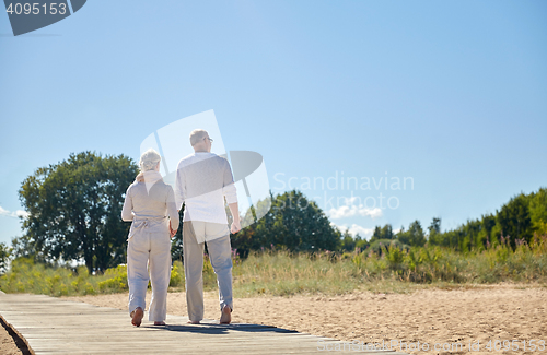 Image of happy senior couple holding hands on summer beach