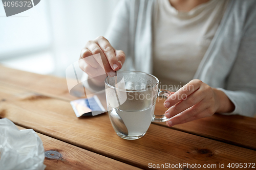 Image of woman stirring medication in cup with spoon