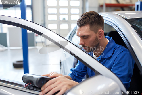 Image of mechanic man with diagnostic scanner at car shop