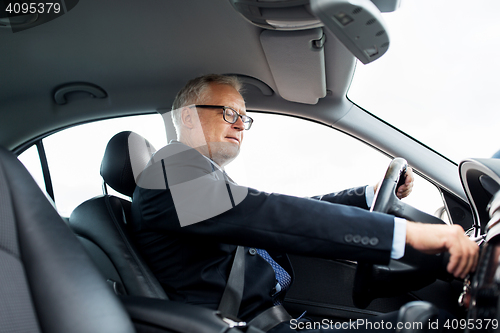 Image of happy senior businessman starting car and driving