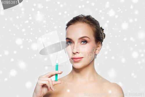 Image of woman holding syringe with injection over snow