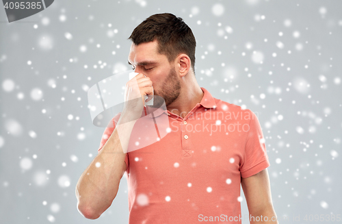 Image of sick man with paper wipe blowing nose over snow
