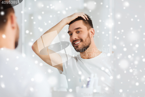 Image of happy young man looking to mirror at home bathroom