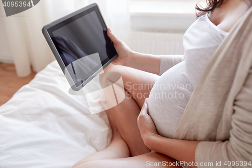 Image of close up of pregnant woman with tablet pc at home