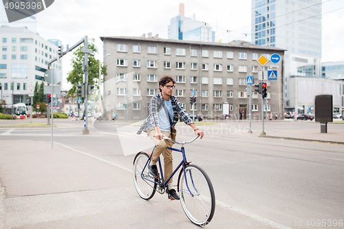 Image of young hipster man with bag riding fixed gear bike