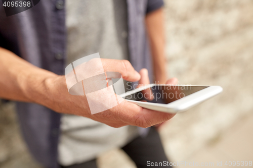 Image of close up of man with smartphone at stone wall