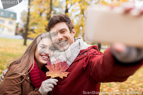 Image of couple taking selfie by smartphone in autumn park