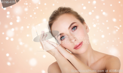 Image of beautiful young woman face and hands over snow