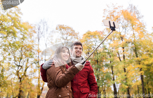 Image of couple taking selfie by smartphone in autumn park