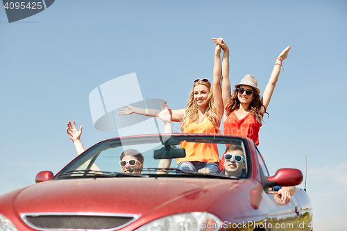 Image of happy friends driving in cabriolet car at country