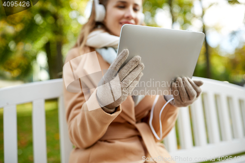 Image of woman with tablet pc and headphones in autumn park